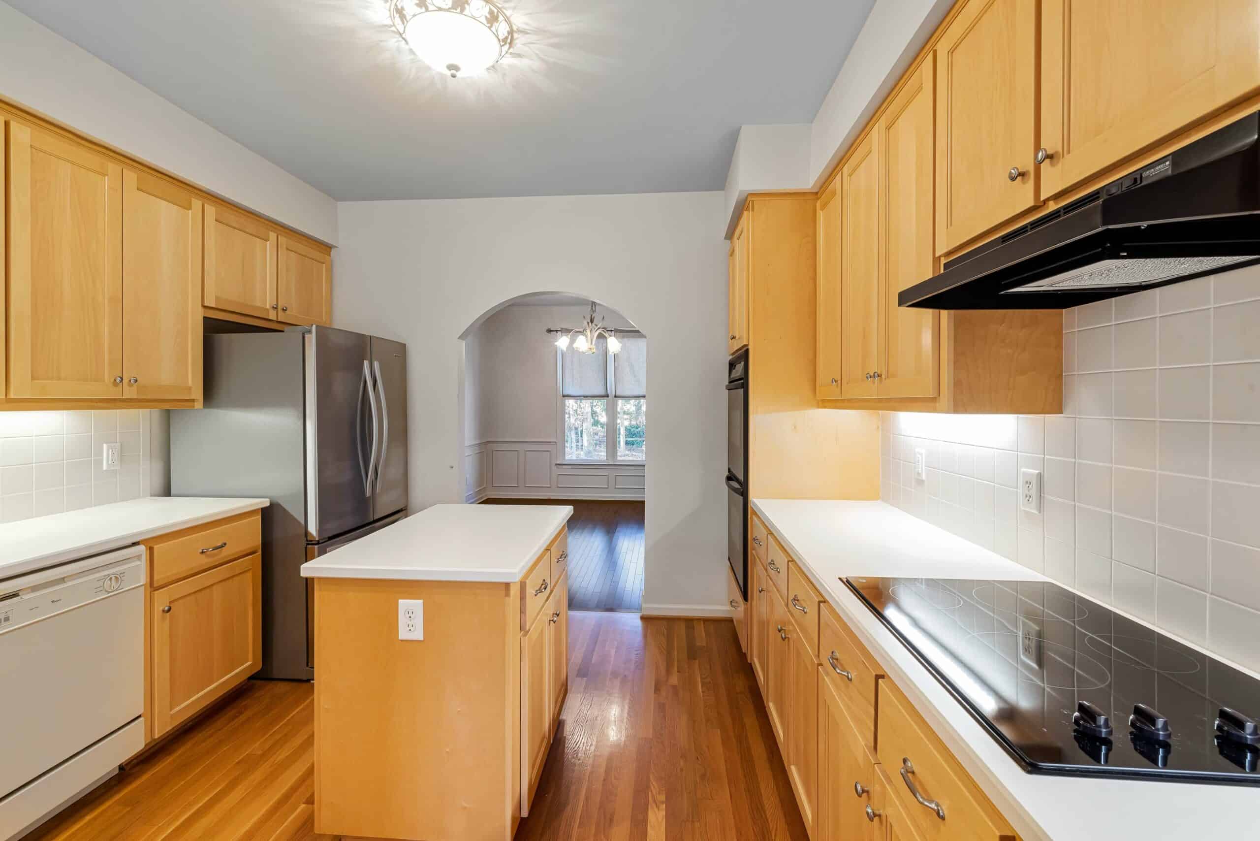 empty kitchen space with clean white counters, lacquered wood cabinets, modern gas stove, and 2-door refrigrator