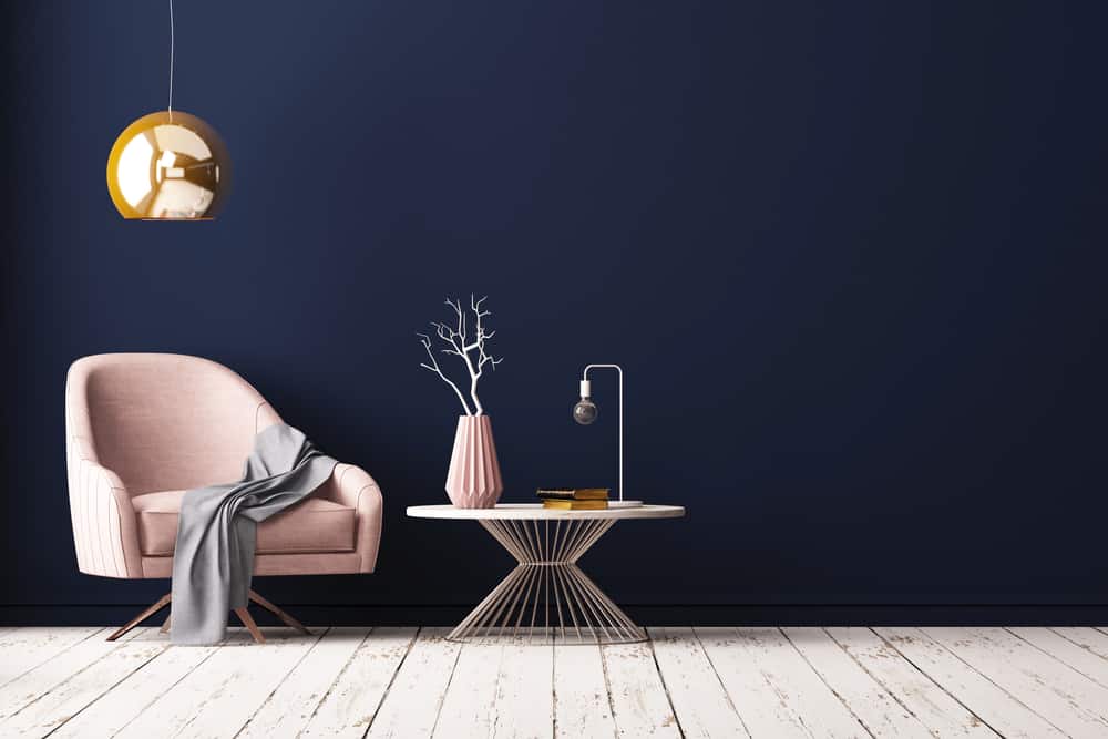 modern pink armchair with navy blue wall paint and a gold hanging pendant light